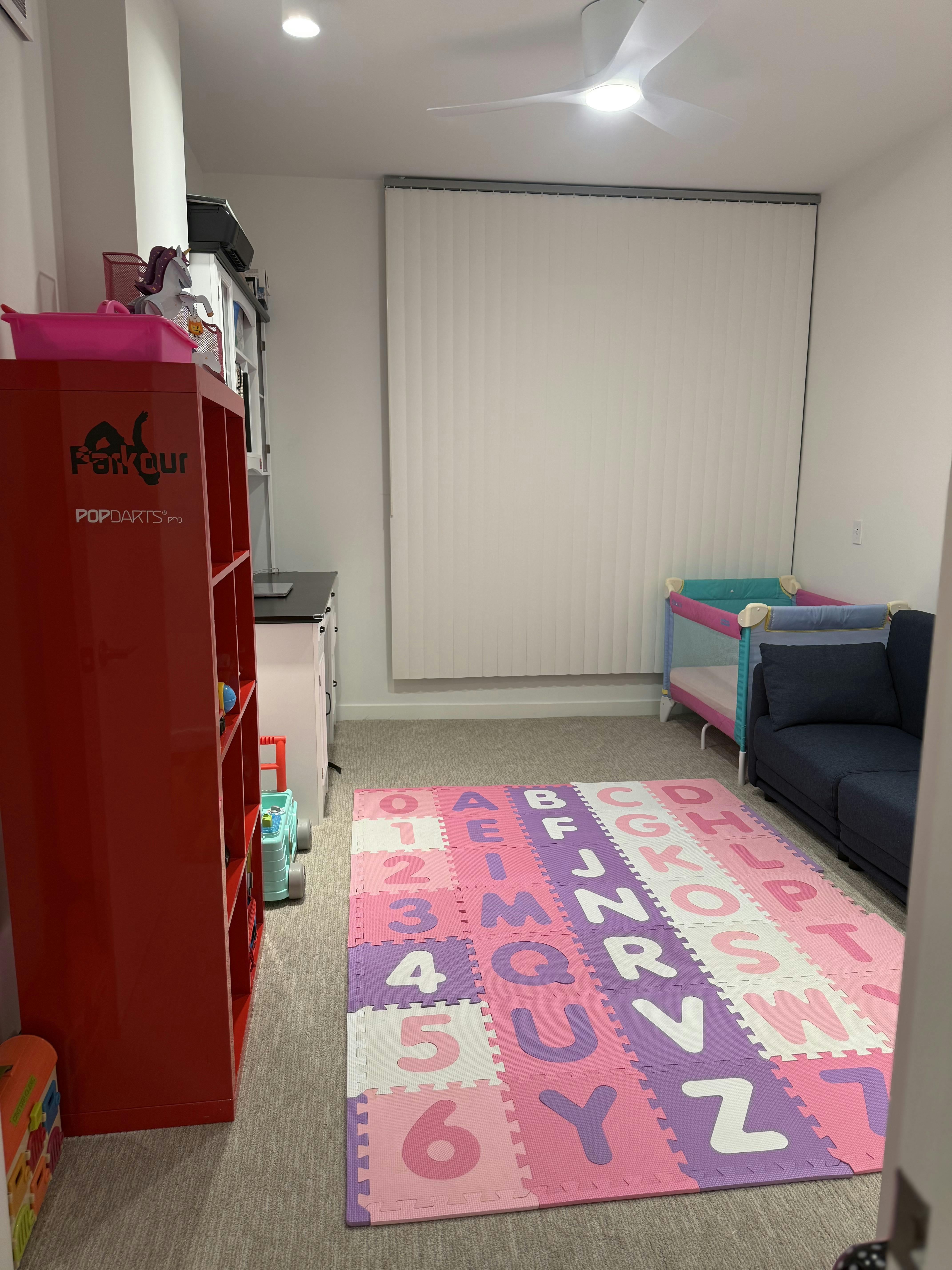 Playroom with alphabet mat, red shelf, crib, and sofa