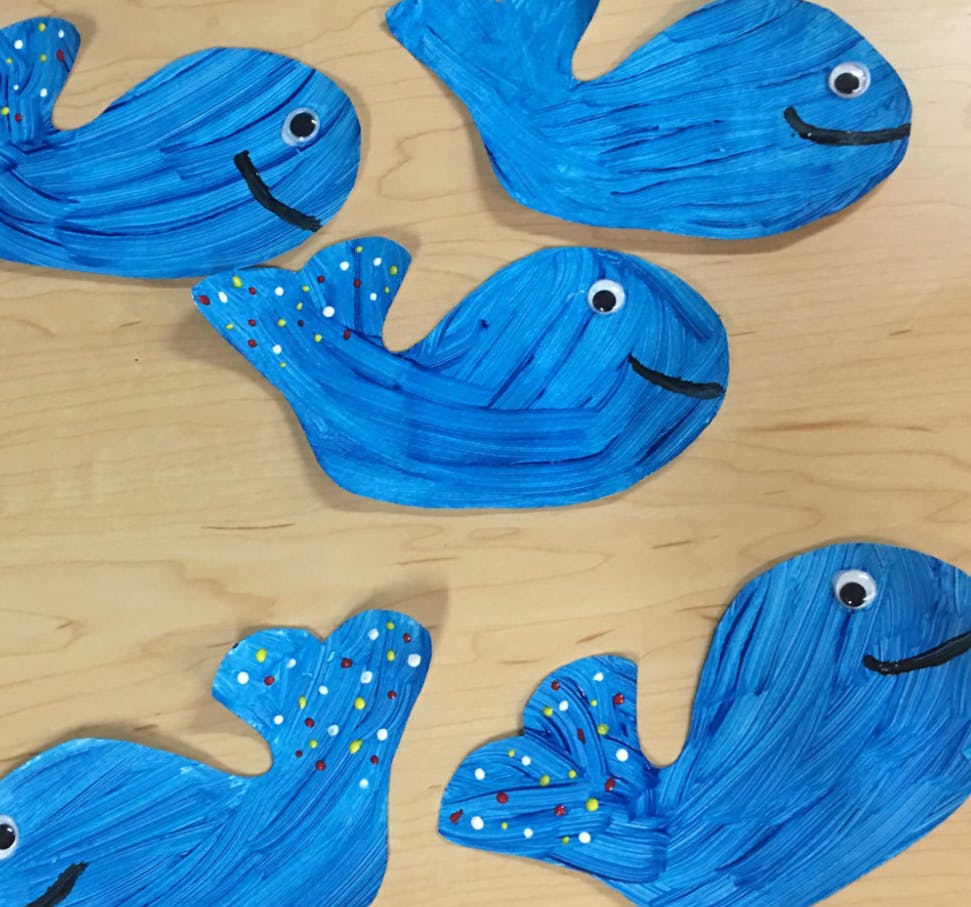 Multiple blue whale cutouts with googly eyes and smiles