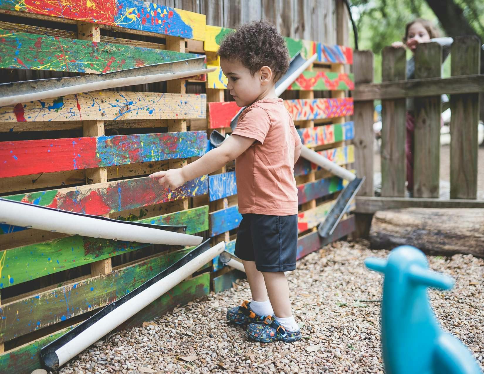 Child playing with pipes on a colorful wooden structure