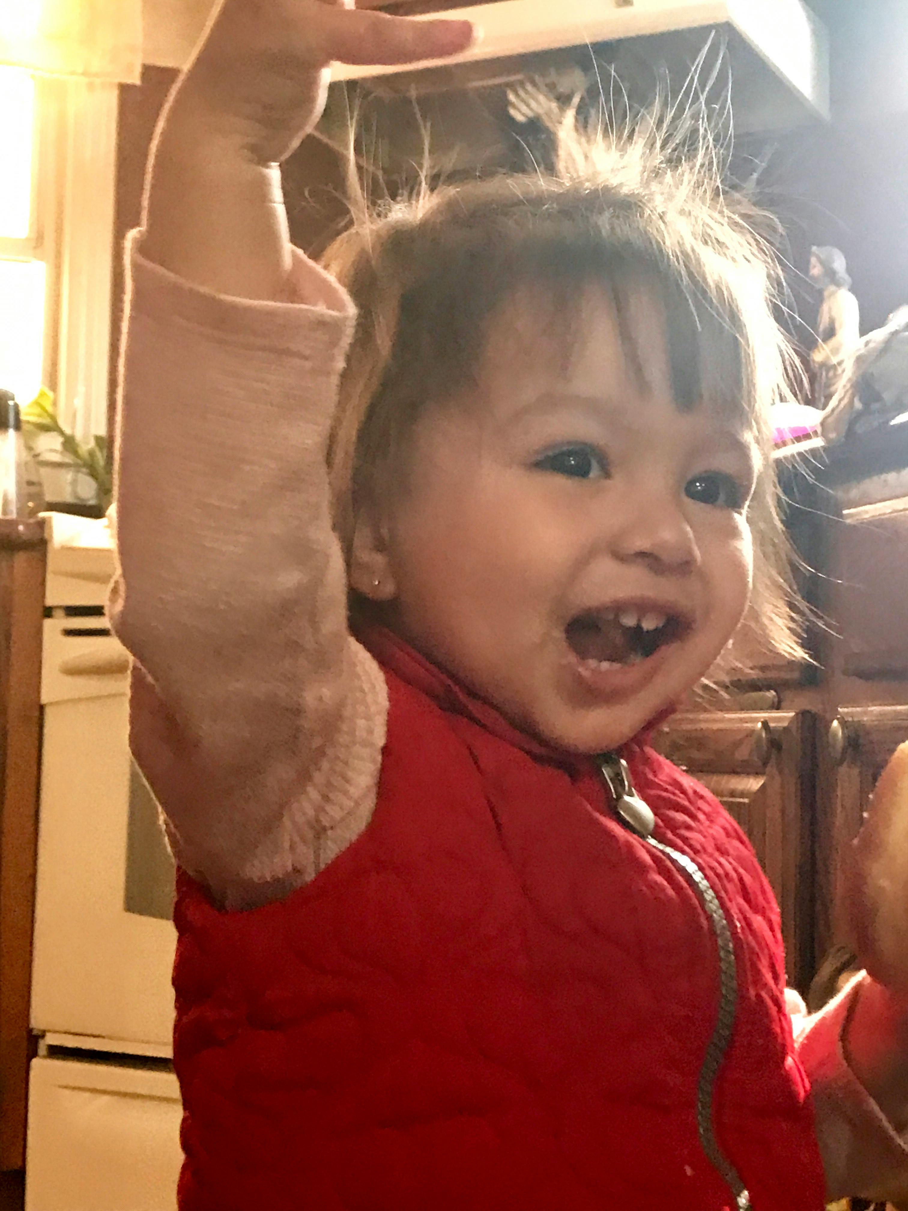 Child with static hair raising an arm