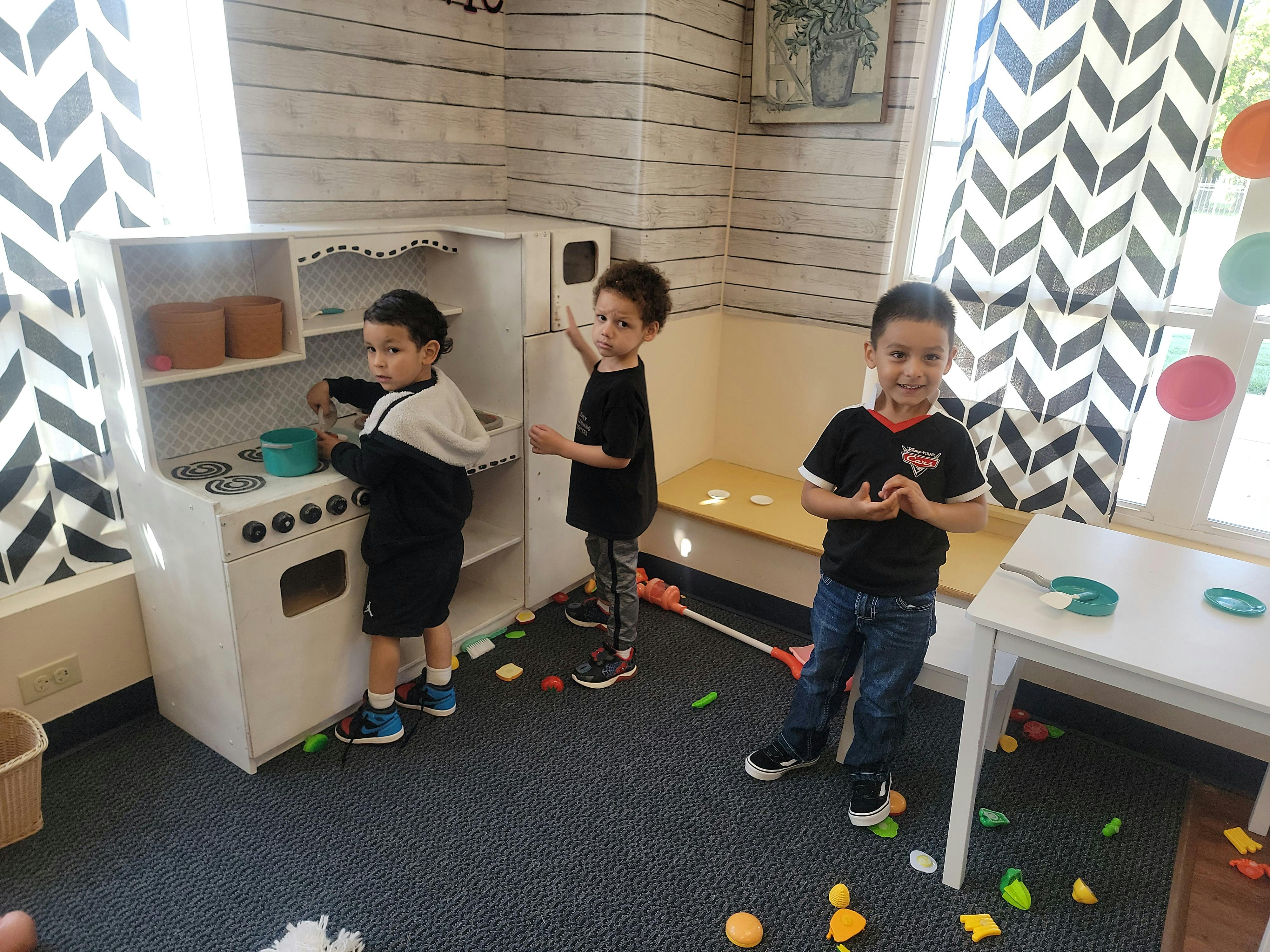 Three children playing in a toy kitchen