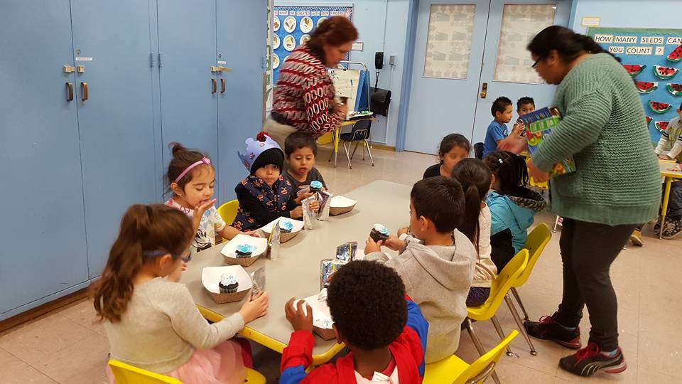 Adults helping children at a table in a classroom