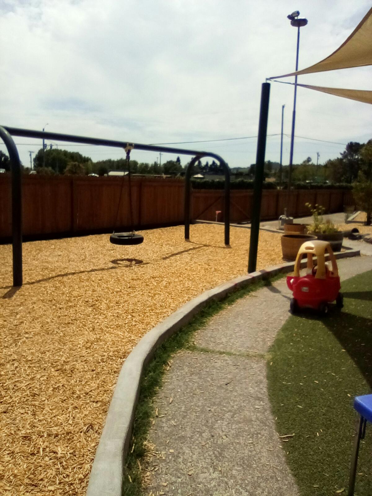 Playground with a tire swing, wood chips, and a red toy car