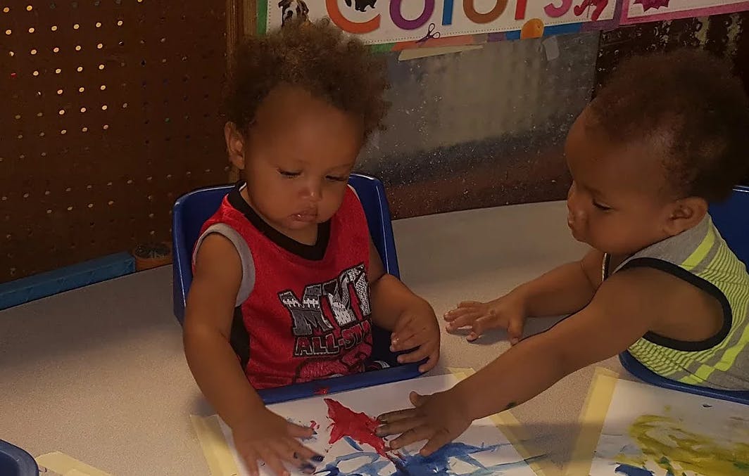 Two children finger painting at a table