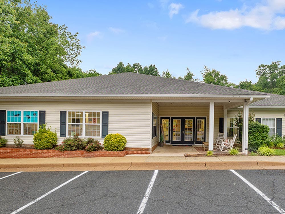 Single-story building with a covered entrance and rocking chairs on the porch