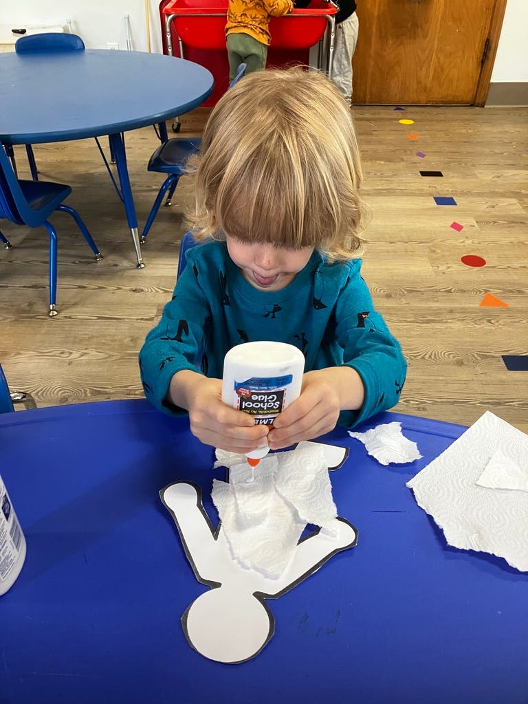 Child applying glue to a paper cutout