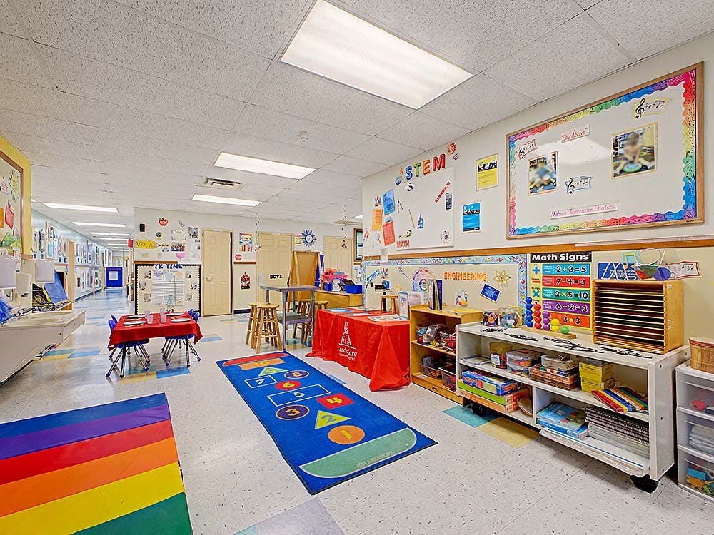 A colorful classroom with play mats, low tables, and educational displays
