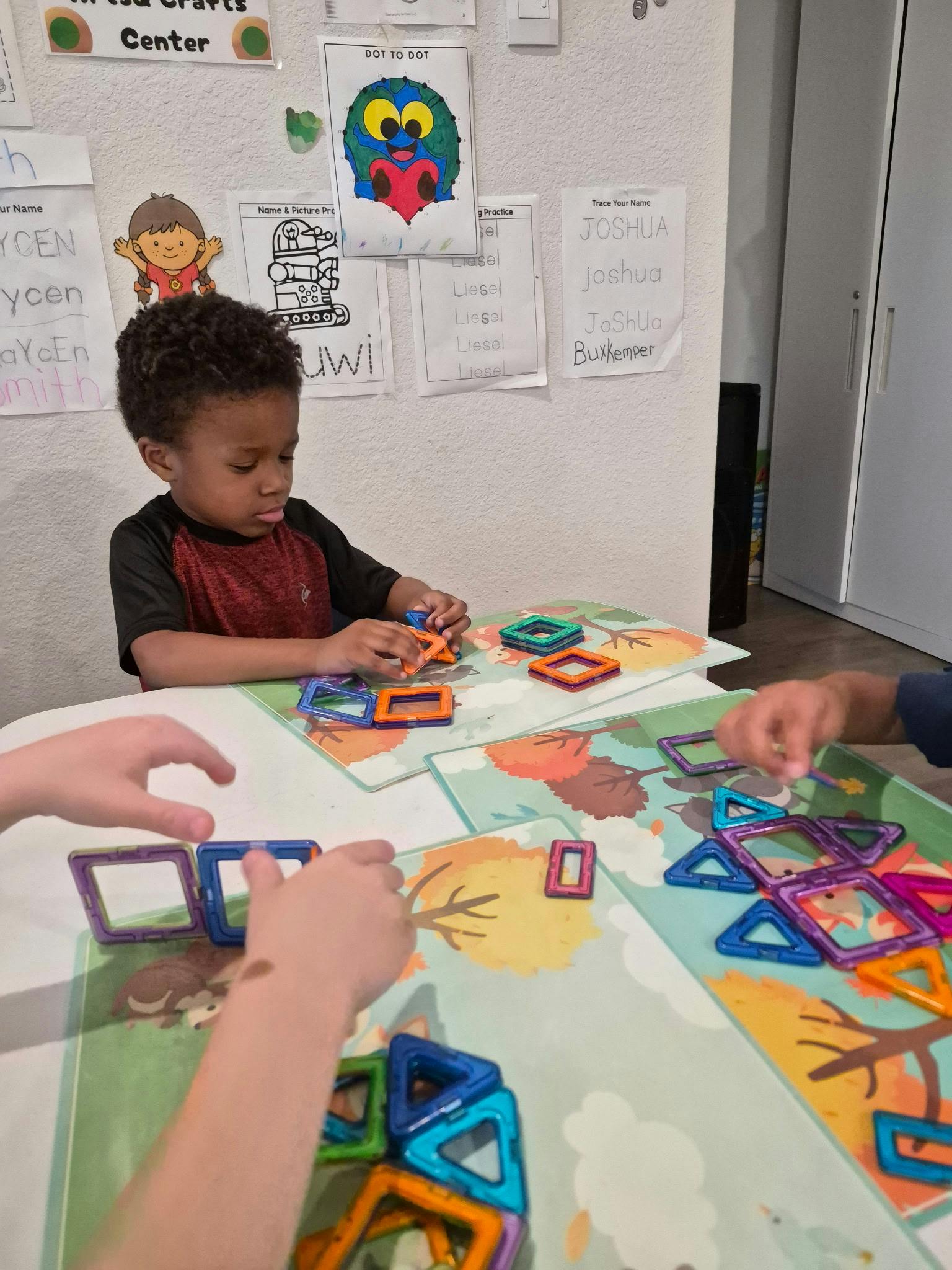 child playing with colorful magnetic tiles at a table
