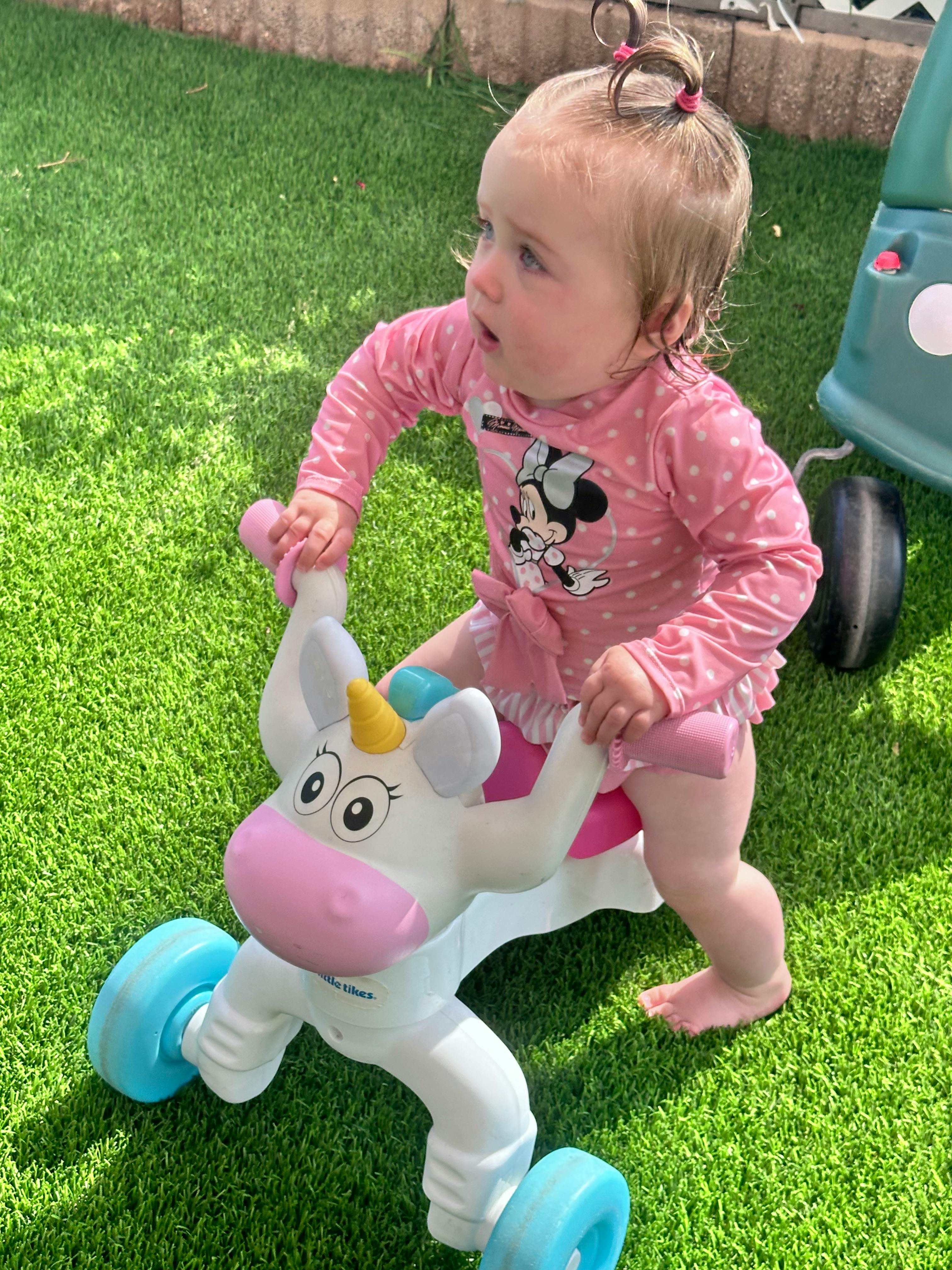 Child on a unicorn ride-on toy on artificial grass