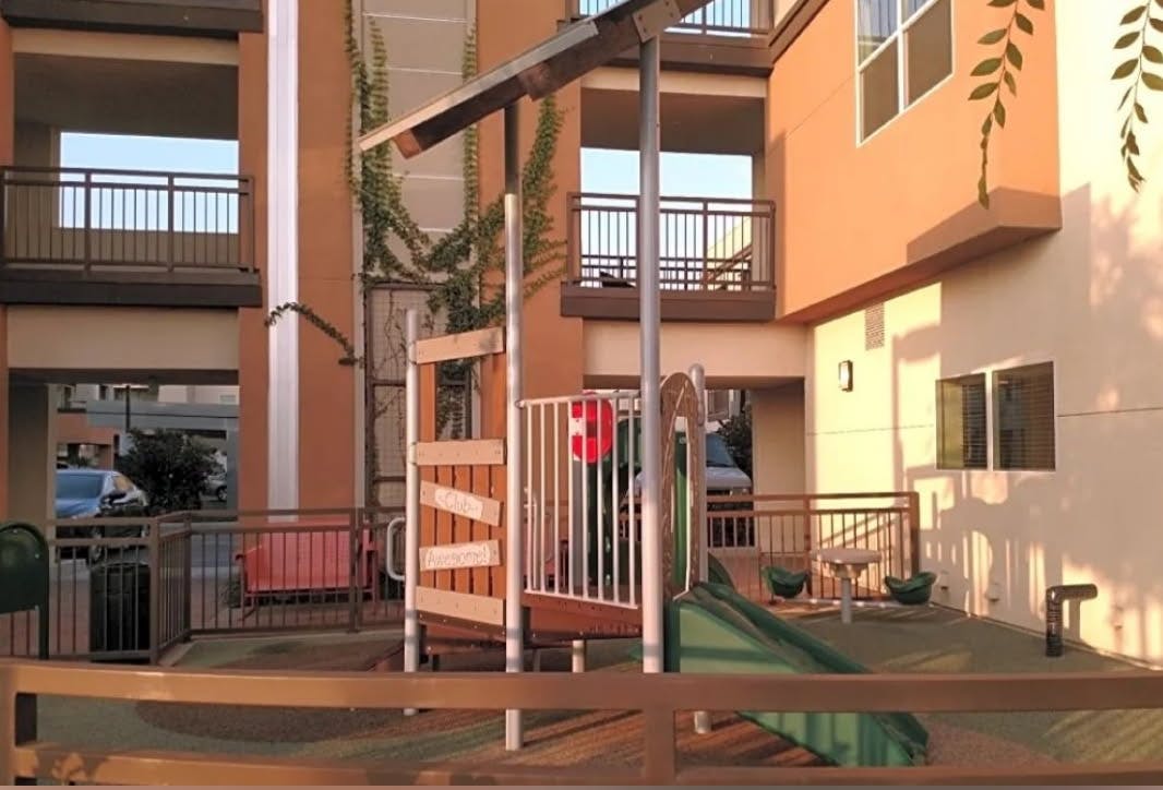 Playground with slide and climbing structure next to a building