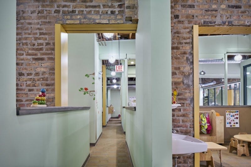 Hallway with brick walls and light green partitions, exit sign visible