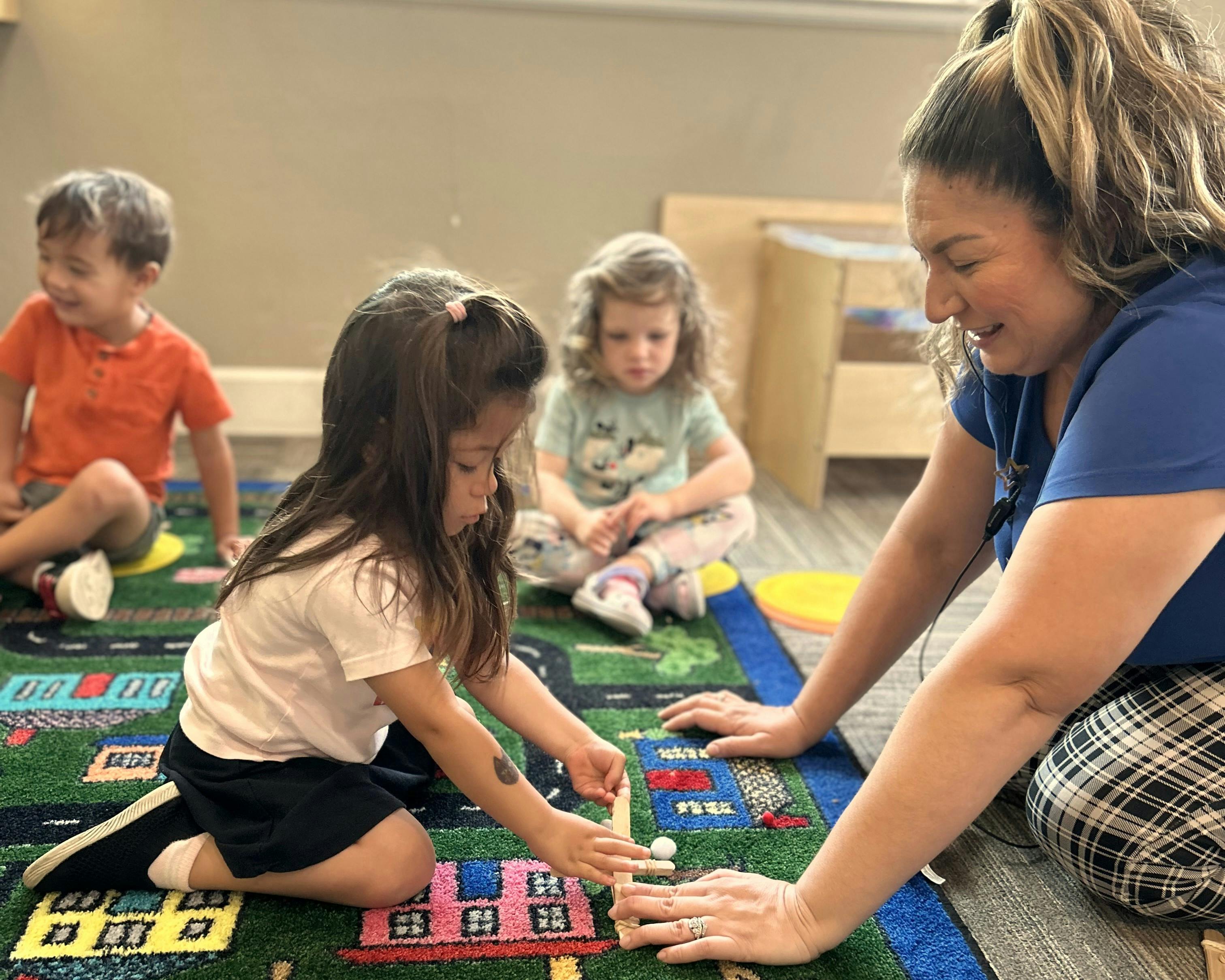 Adult and child playing with building blocks on a rug