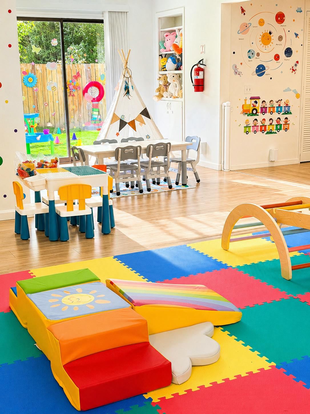 Colorful playroom with soft climbing blocks, small tables, and a teepee