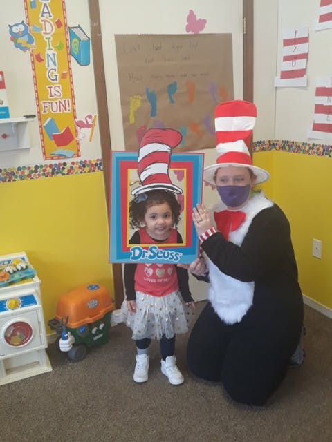 Person in Cat in the Hat costume with child holding Dr Seuss cutout