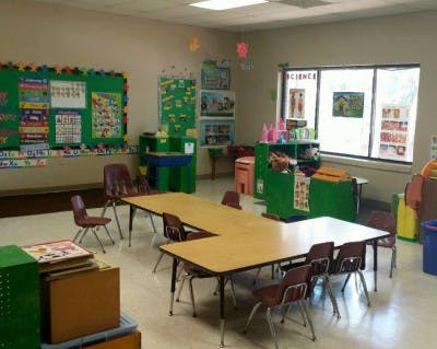 Classroom with tables and chairs, green bulletin boards, and a window