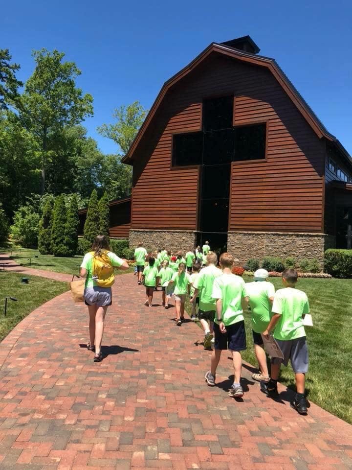 People walking on a brick path towards a building with a large cross on it