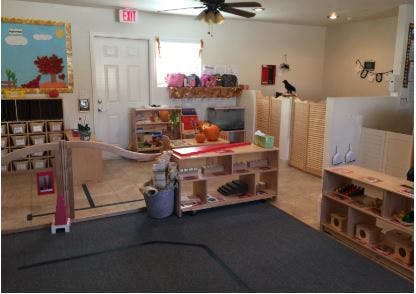 A classroom with wooden shelves, toys, and a play area