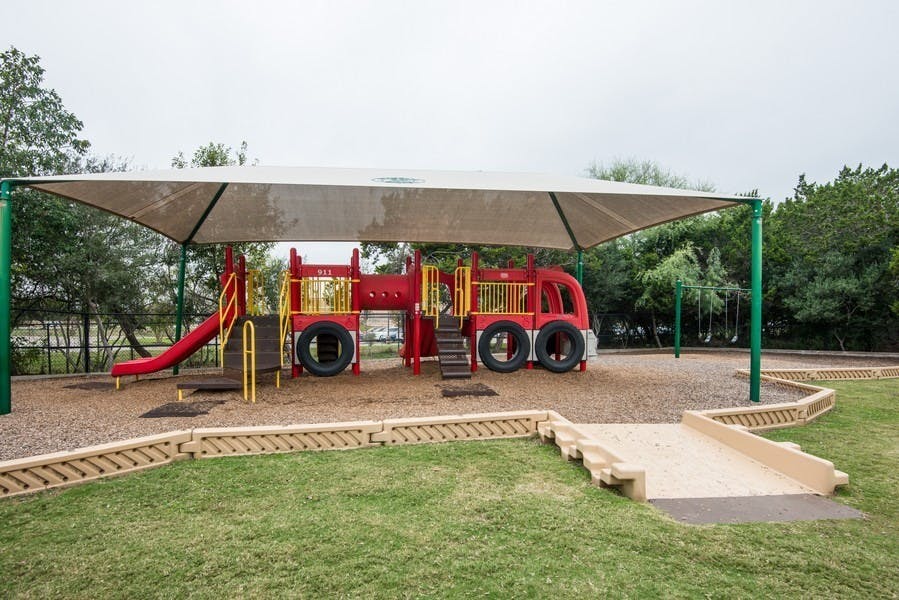 Red fire truck themed playground under a shade structure