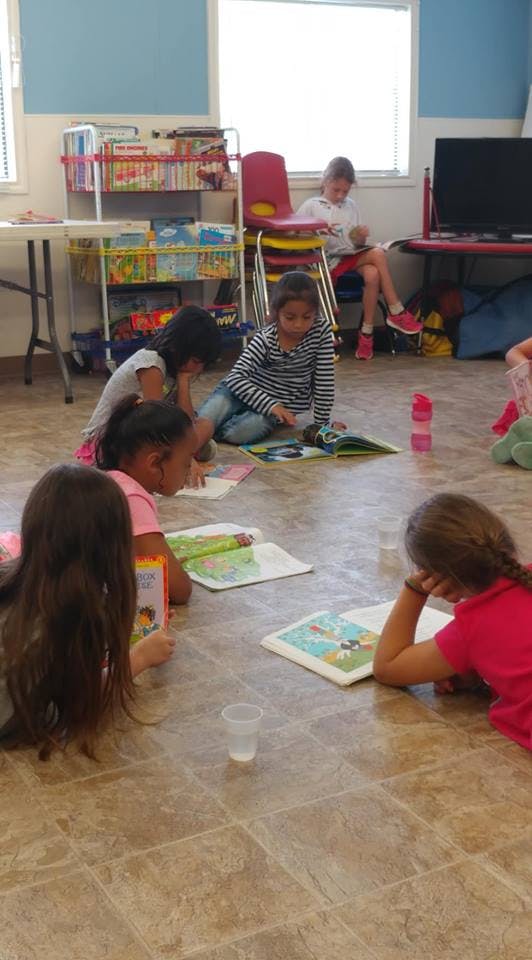 Children reading books on the floor in a classroom