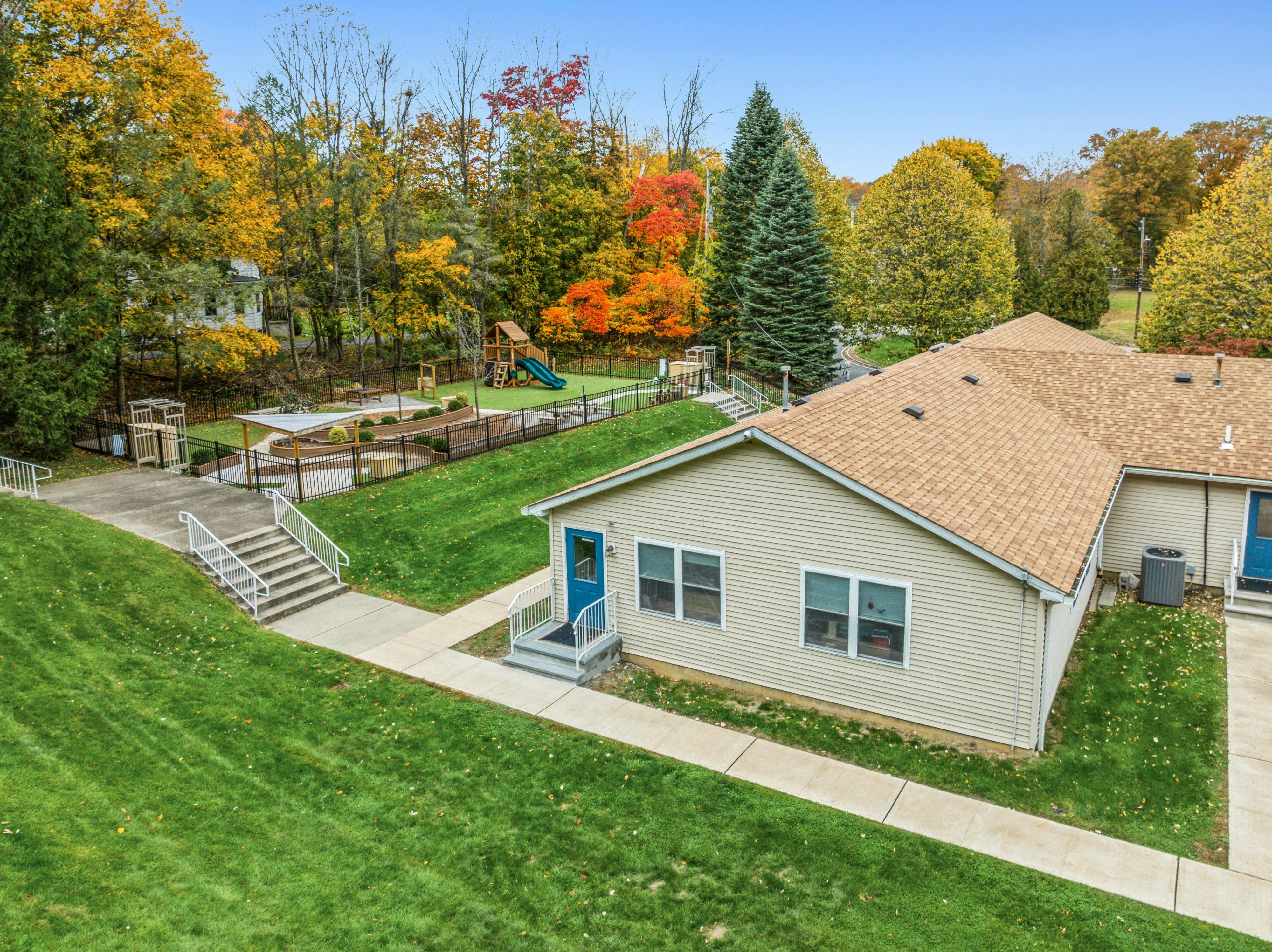 Aerial view of a building with a brown roof and a fenced playground