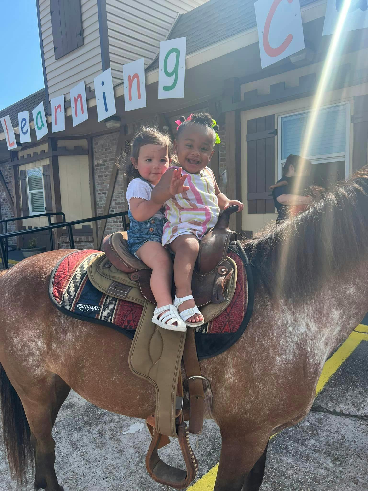Two children riding a horse with a saddle