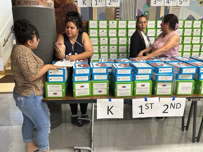 Three people at a table filled with boxes of chocolate