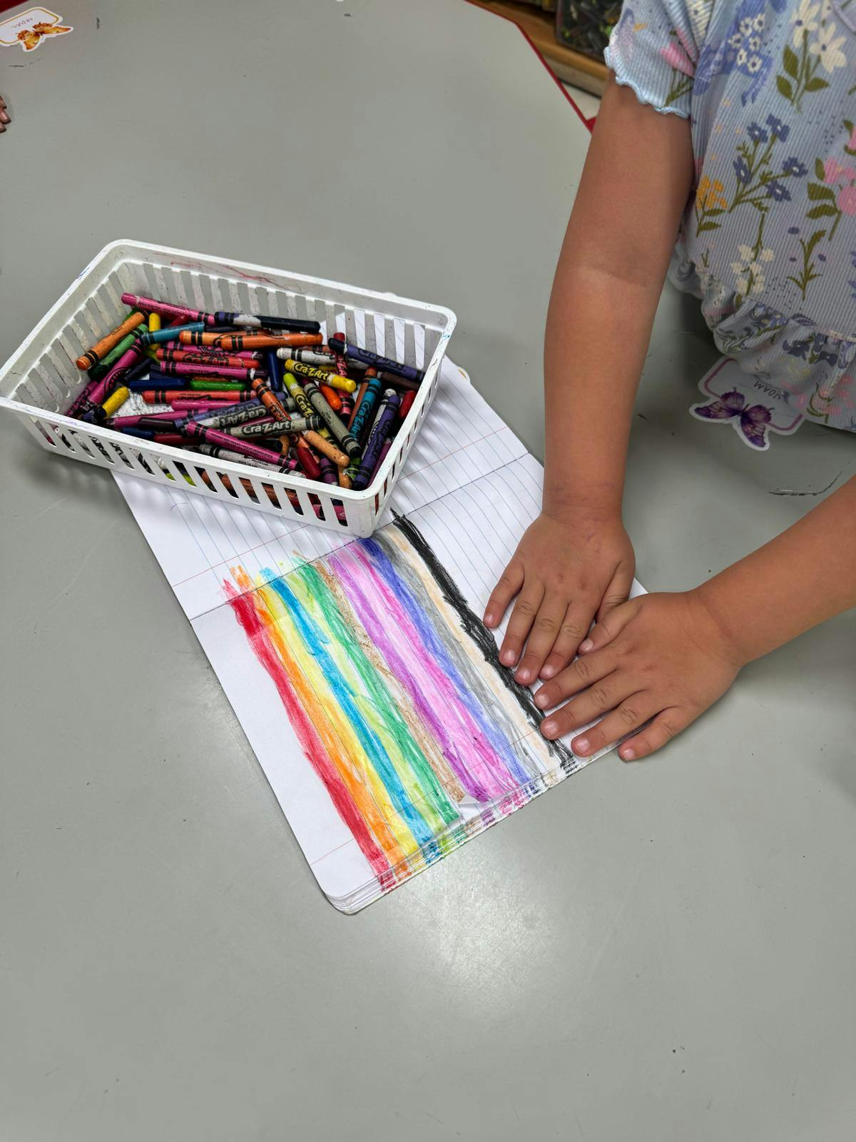 Child coloring with crayons on a notebook