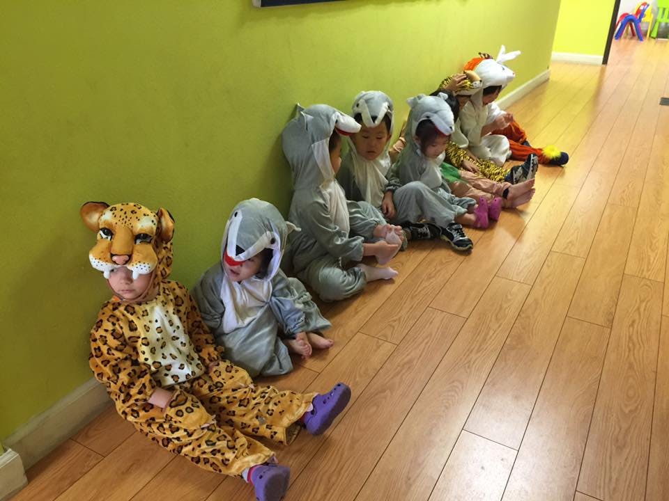 Children in animal costumes sitting on a wooden floor