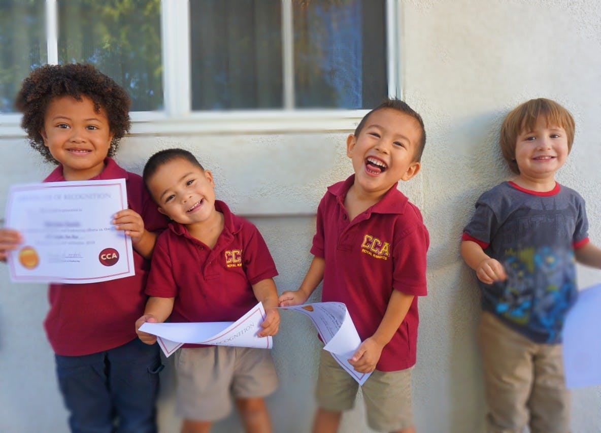 Four children holding papers, one holding a certificate
