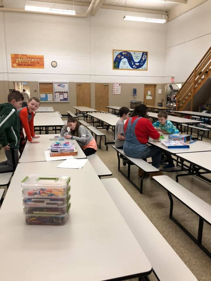 Children and adults sitting at tables in a large room