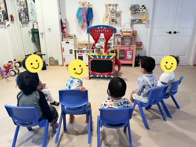Children sitting in chairs watching a puppet theater