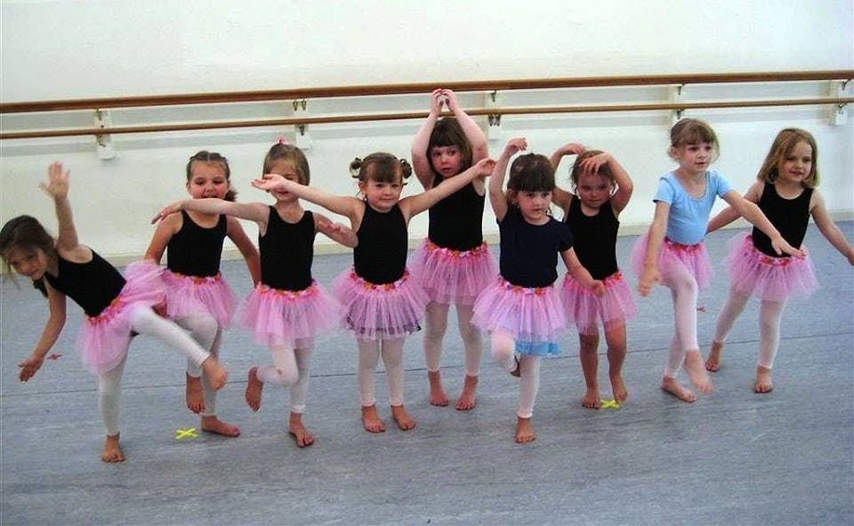 Group of children in ballet attire posing in a dance studio