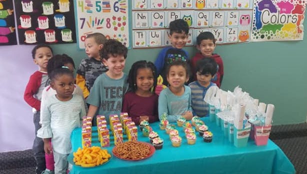 Group of children standing behind a table with snacks and snacks