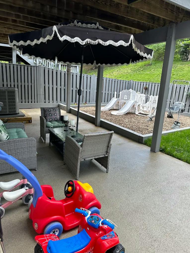 Patio furniture set under an umbrella with ride-on toys and a child play area