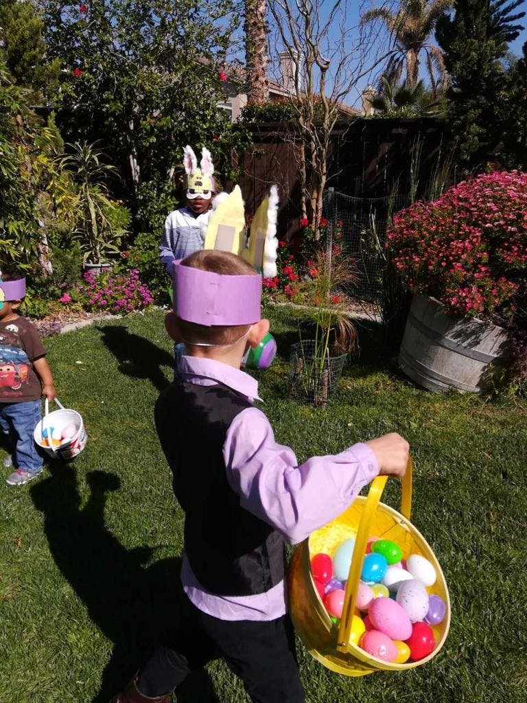 Child in a purple crown holding a basket of colorful eggs