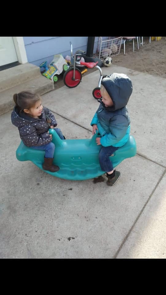 Two children on a teal rocking toy