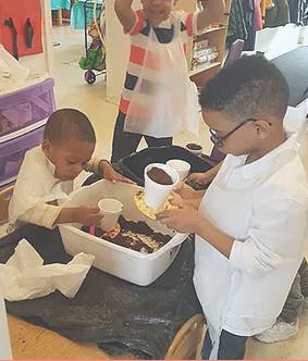 Three children playing with soil and cups