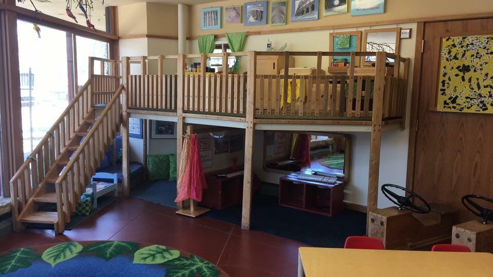 Indoor play area with wooden stairs leading to an elevated platform