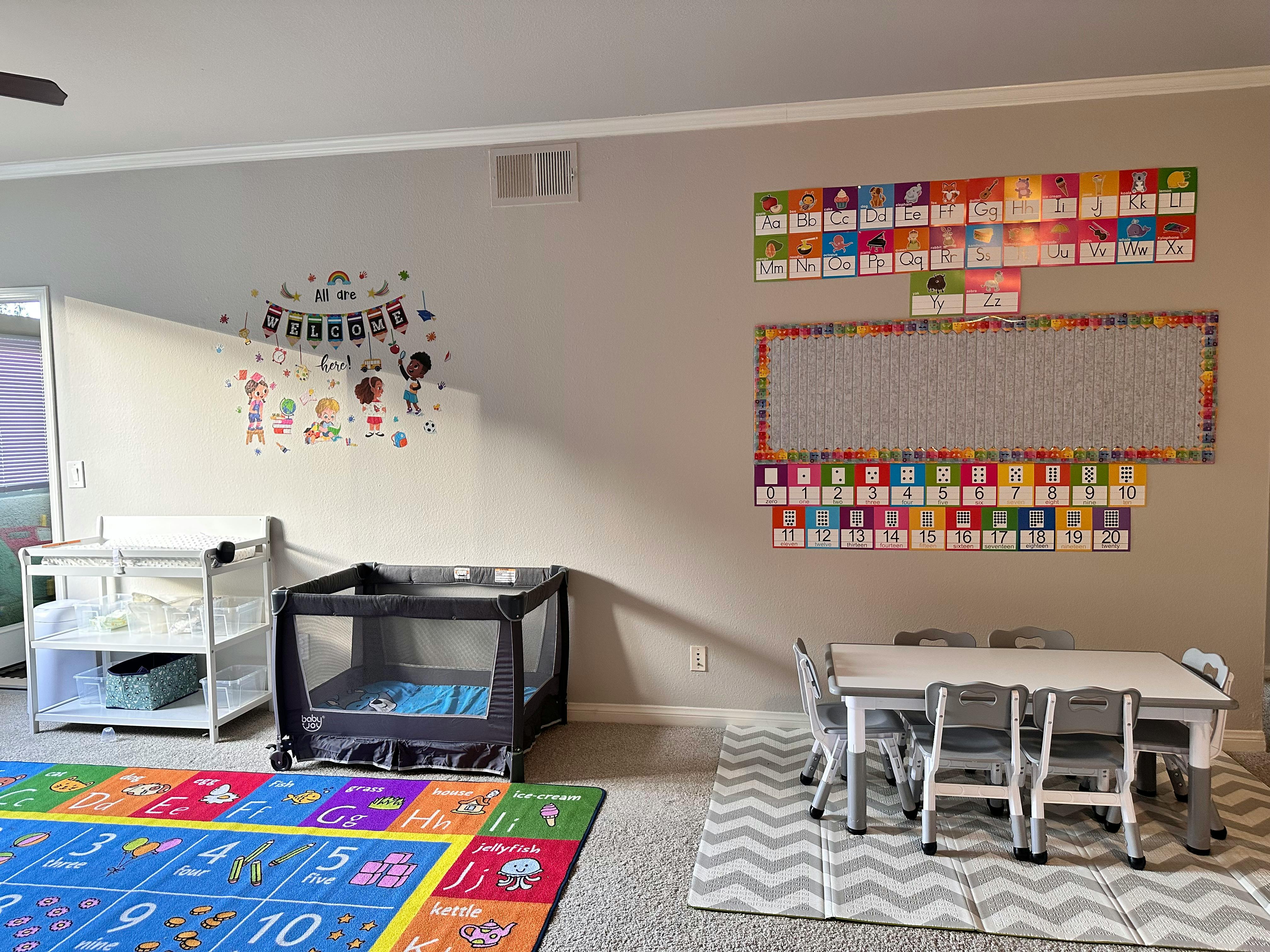 Playroom with a changing table, playpen, alphabet rug, and small table with chairs