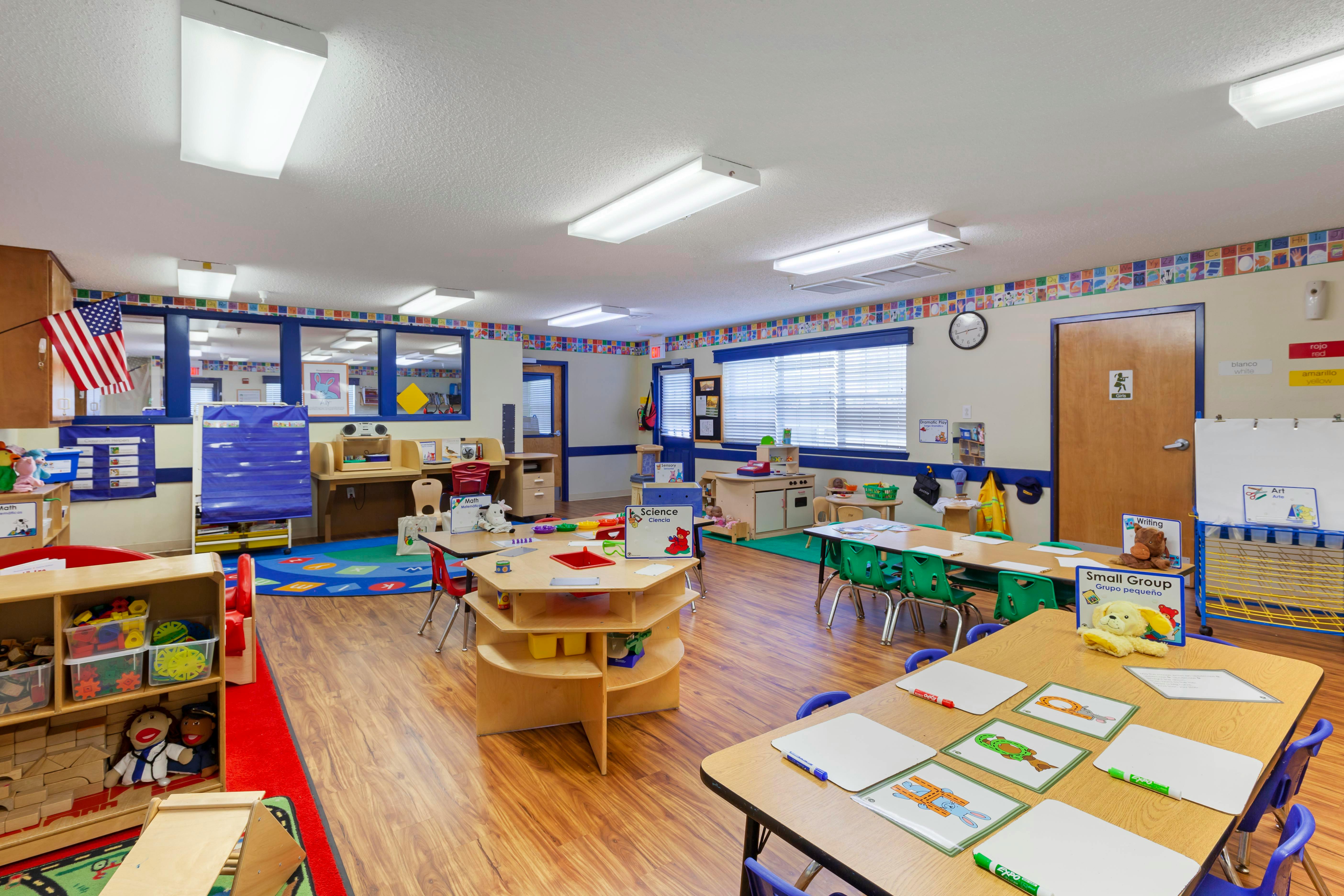 A colorful empty preschool classroom with small tables and chairs