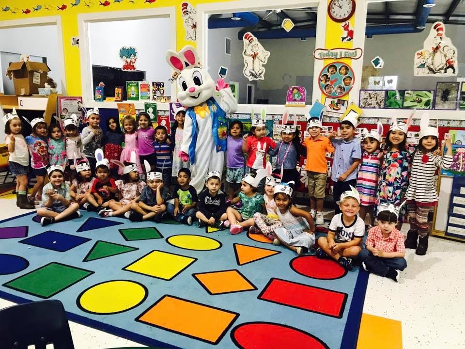 Children and a person in a bunny costume posing for a photo in a classroom