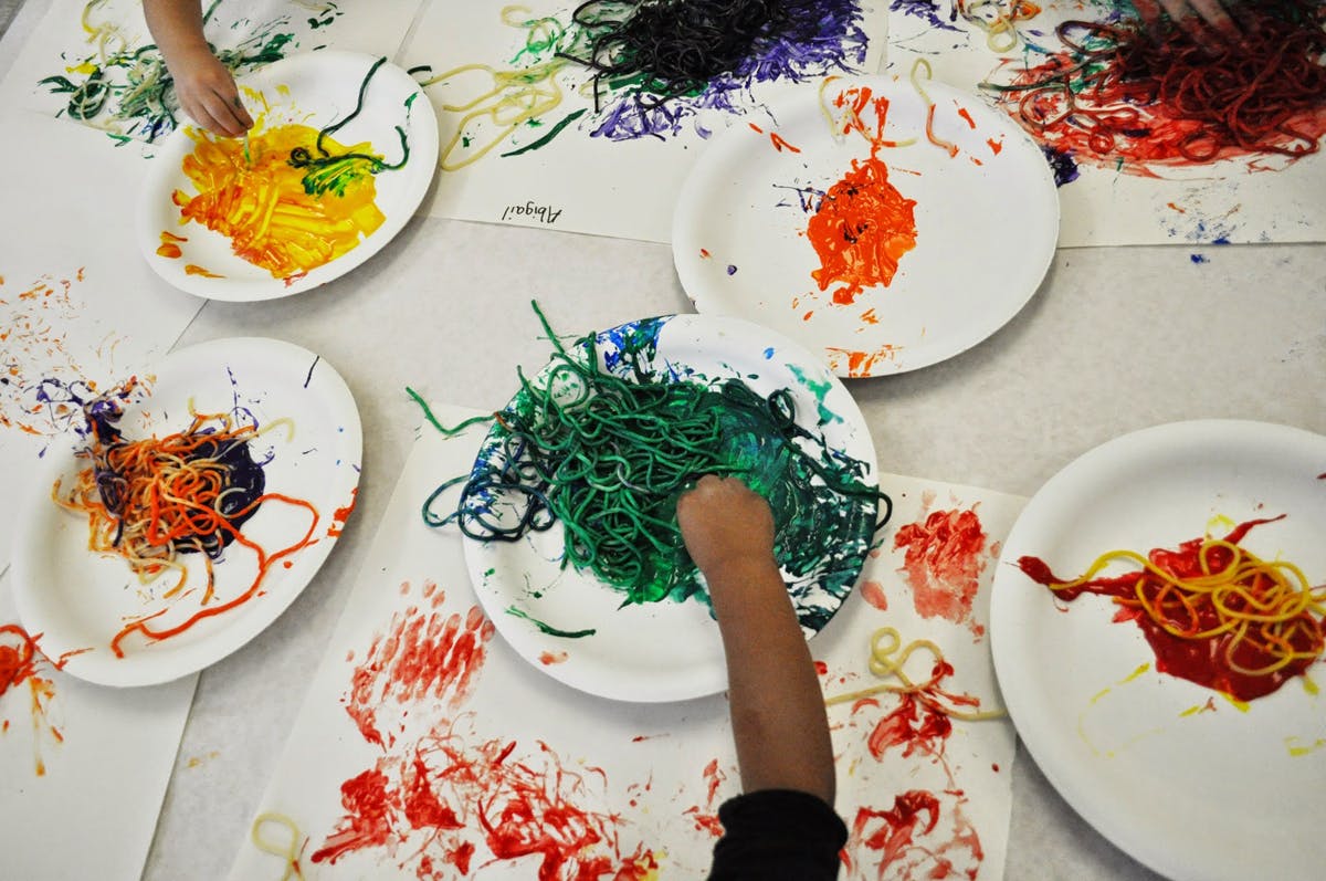 Children's hands playing with colorful string on paper plates