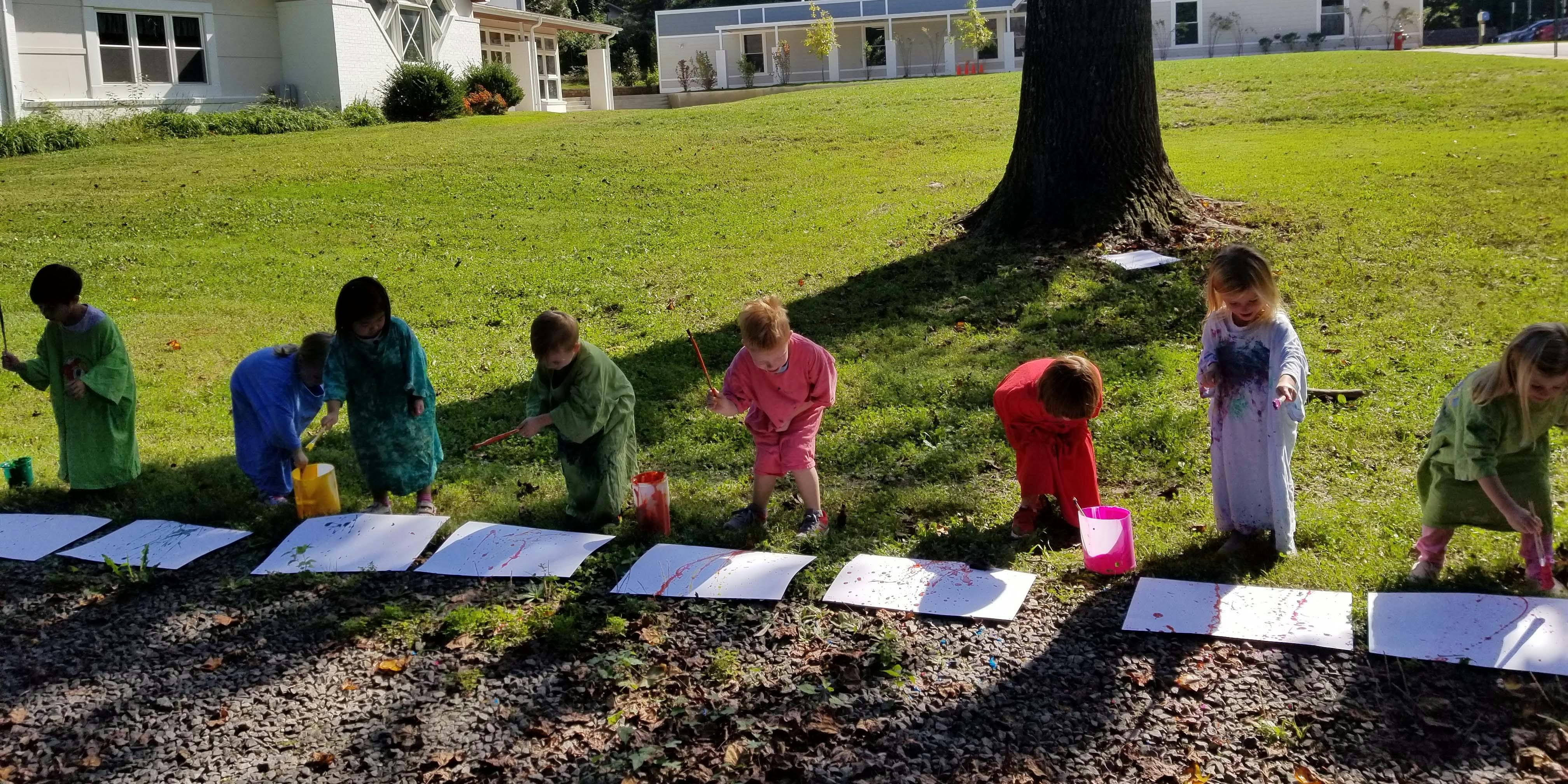 Children painting on paper outdoors