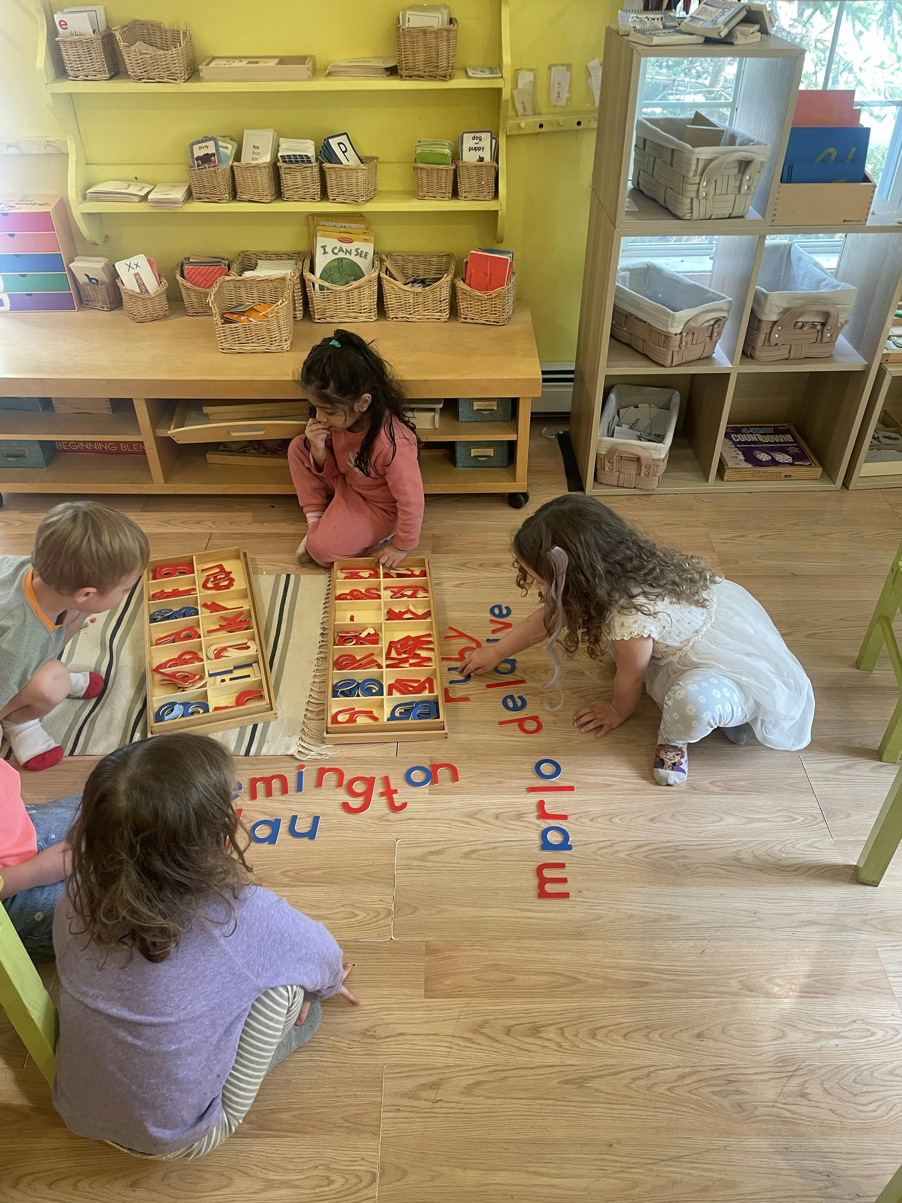Children sitting on the floor using colorful plastic letters to form words