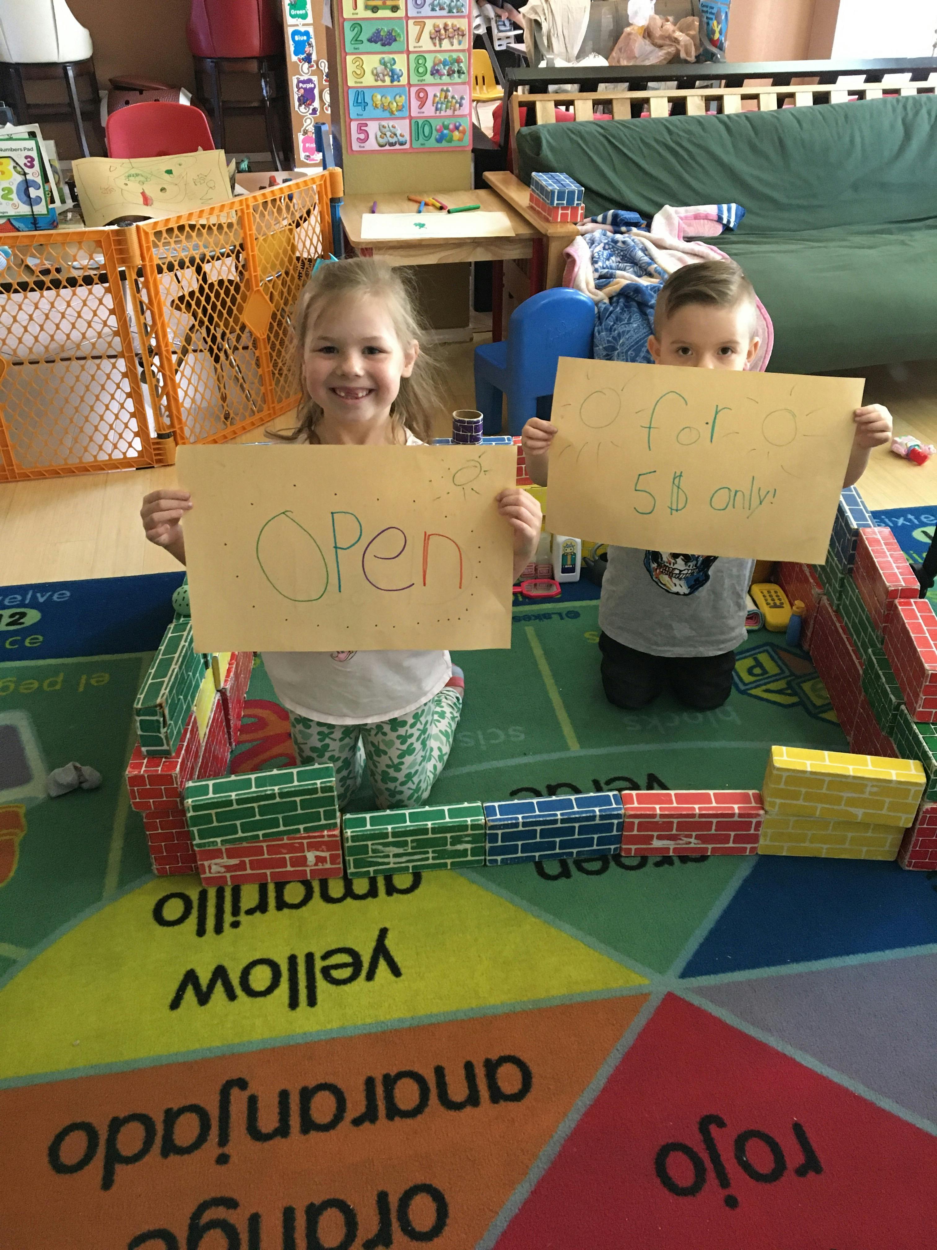 Two children holding signs, one reading "OPEN" and the other "for $5 only"
