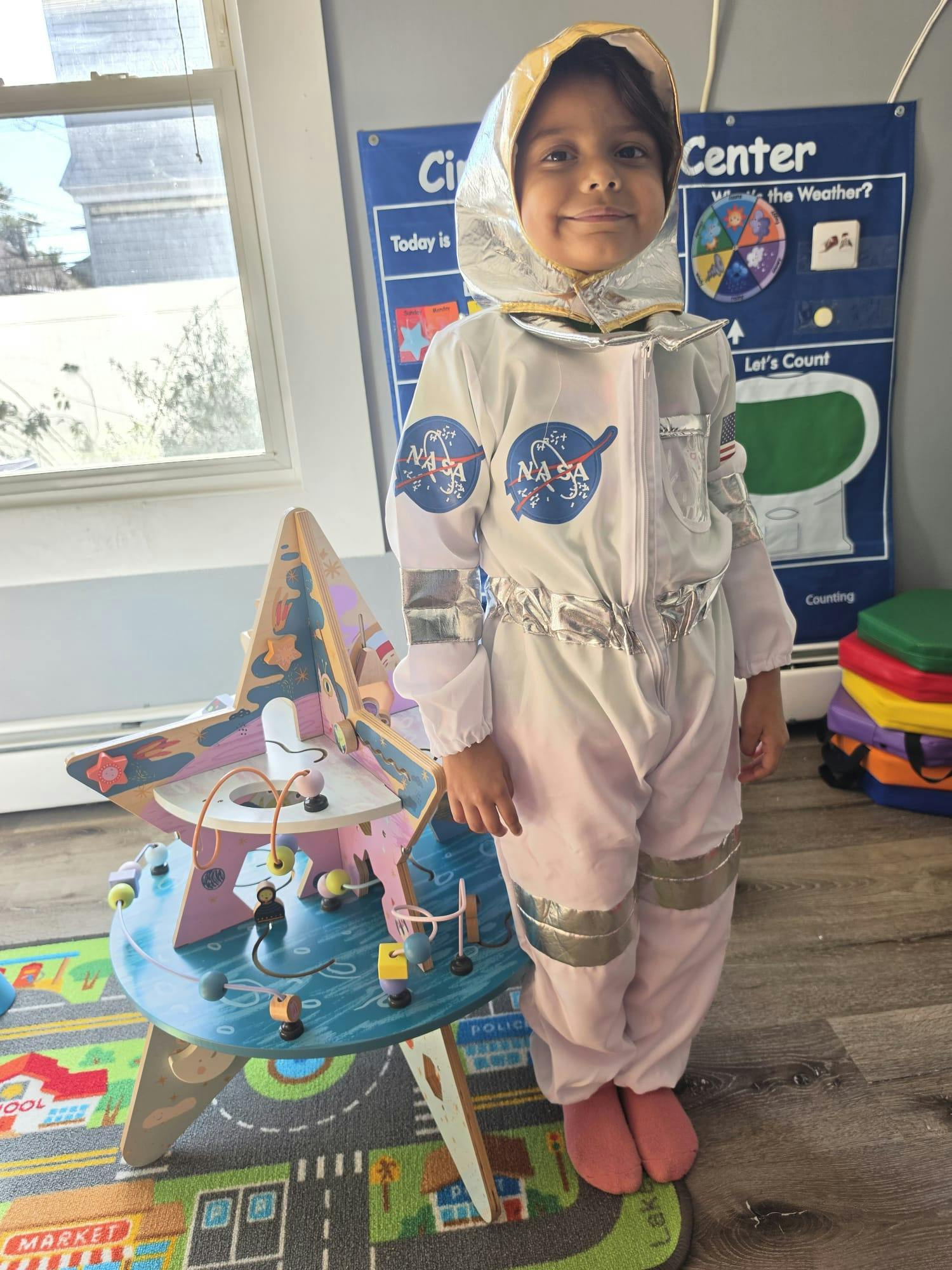Child wearing an astronaut costume standing by a star-shaped activity toy