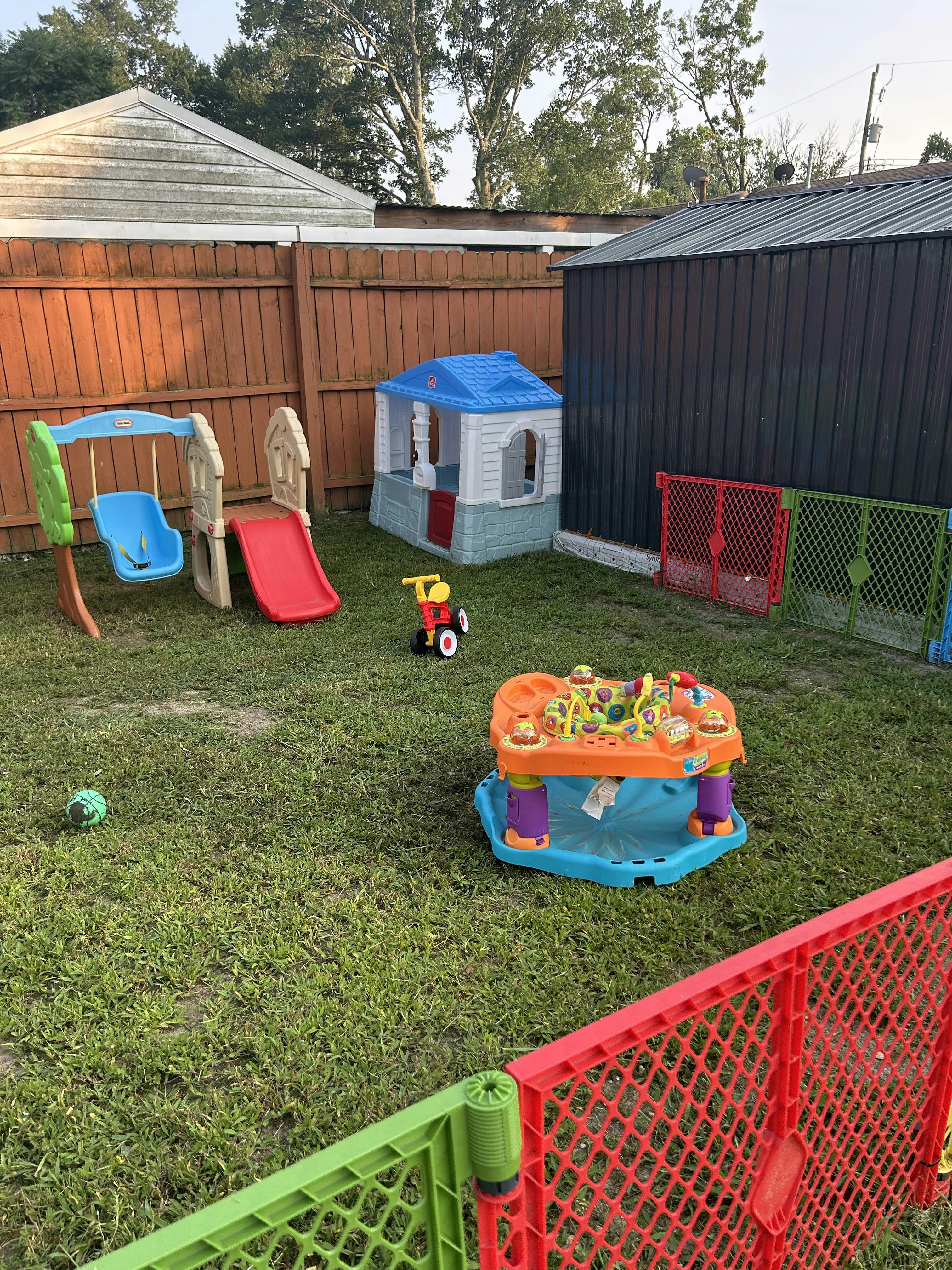 Plastic playground equipment and toys in a fenced backyard