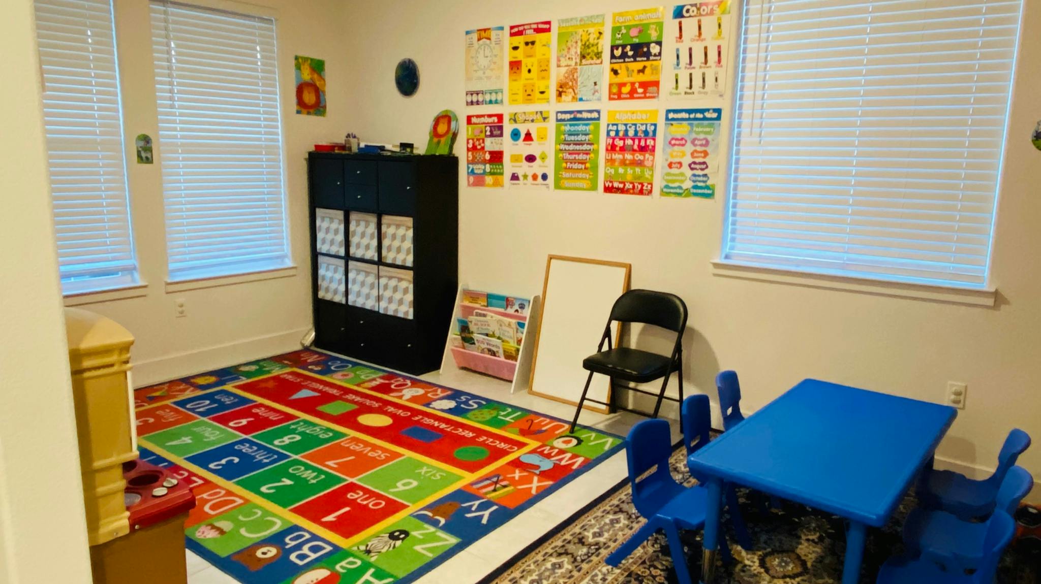 Child's play area with colorful alphabet rug and small blue table and chairs