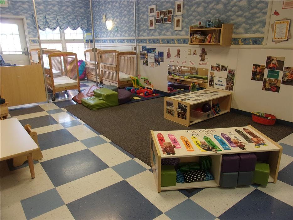 cribs, play mats, and toys in a childcare room
