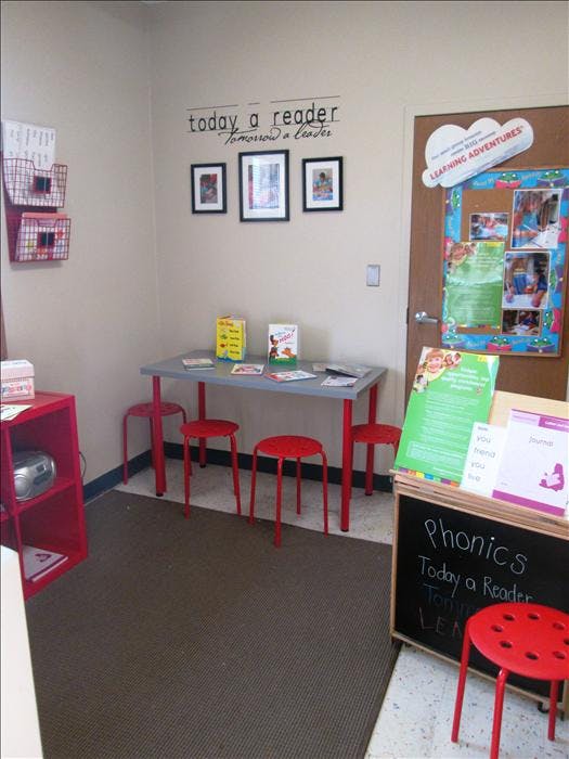 Classroom space with a table, red stools, and books